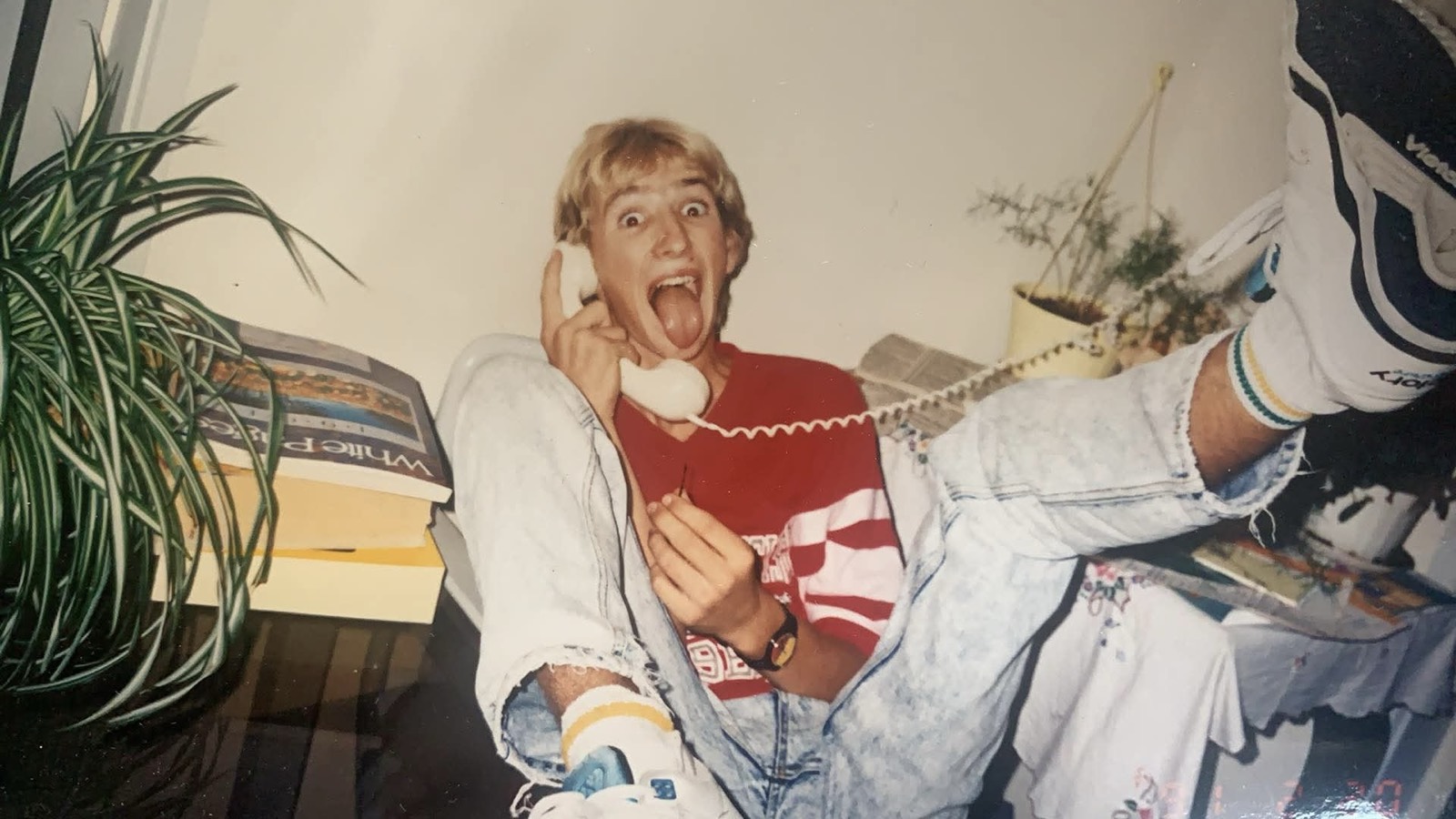 Gordon as a teenager around 1990, grinning wide with his tongue out on a corded telephone